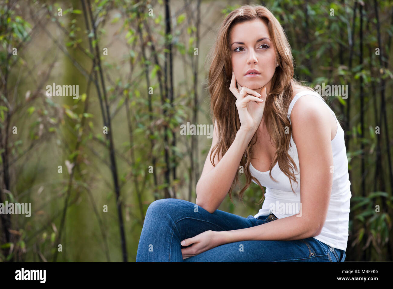 Junge Frau denken und sein Blick in die Ferne draußen sitzen Stockfoto
