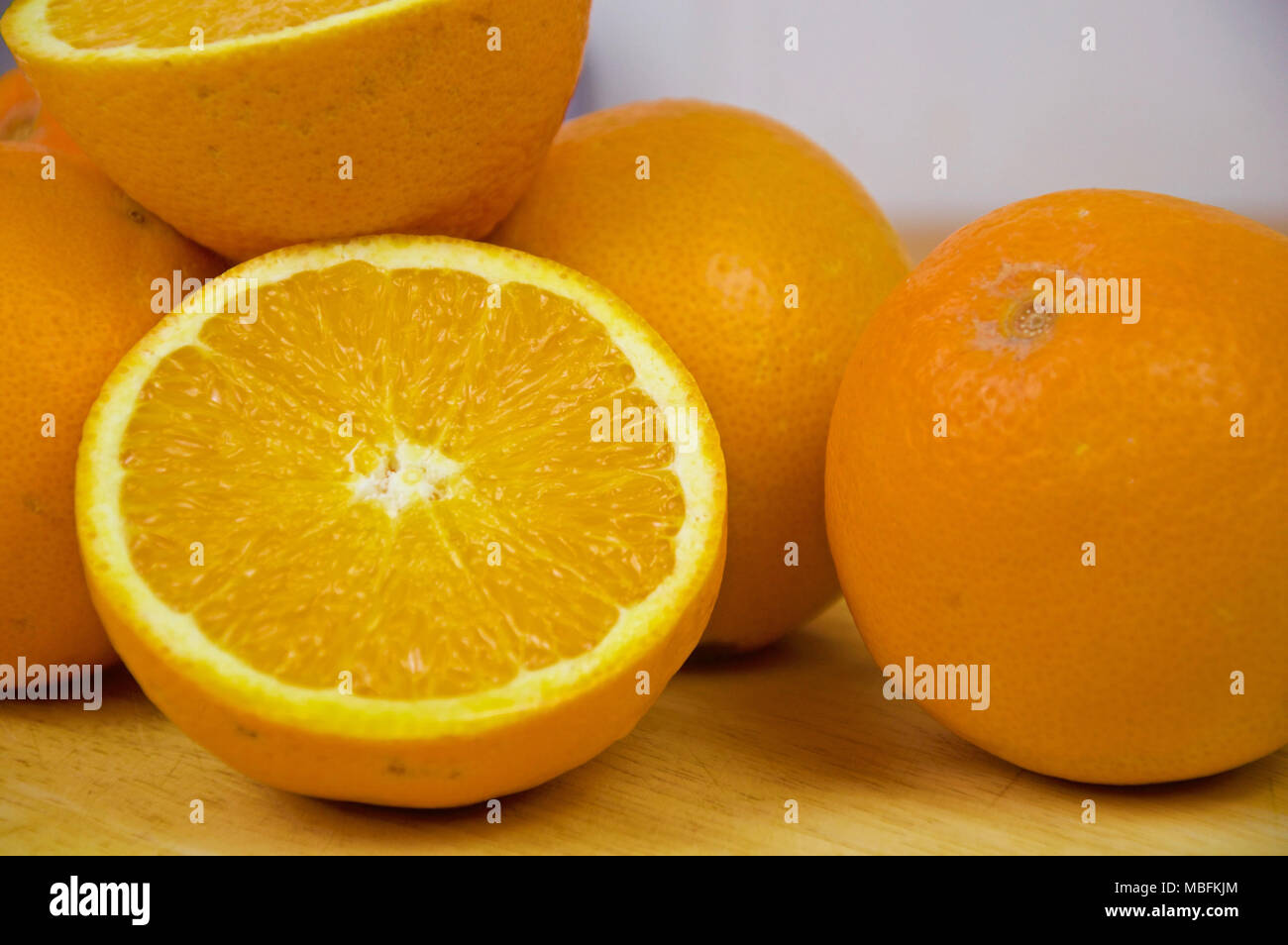 Mehrere Orangen und einem Schnitt in der Hälfte auf einem Tisch Stockfoto