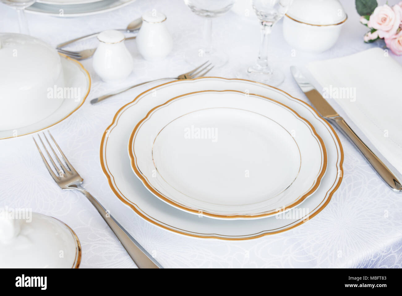 Wunderschön dekorierten Tisch mit weißer Teller, Gläser, Besteck und Blumen auf luxuriösen Tischdecken Stockfoto