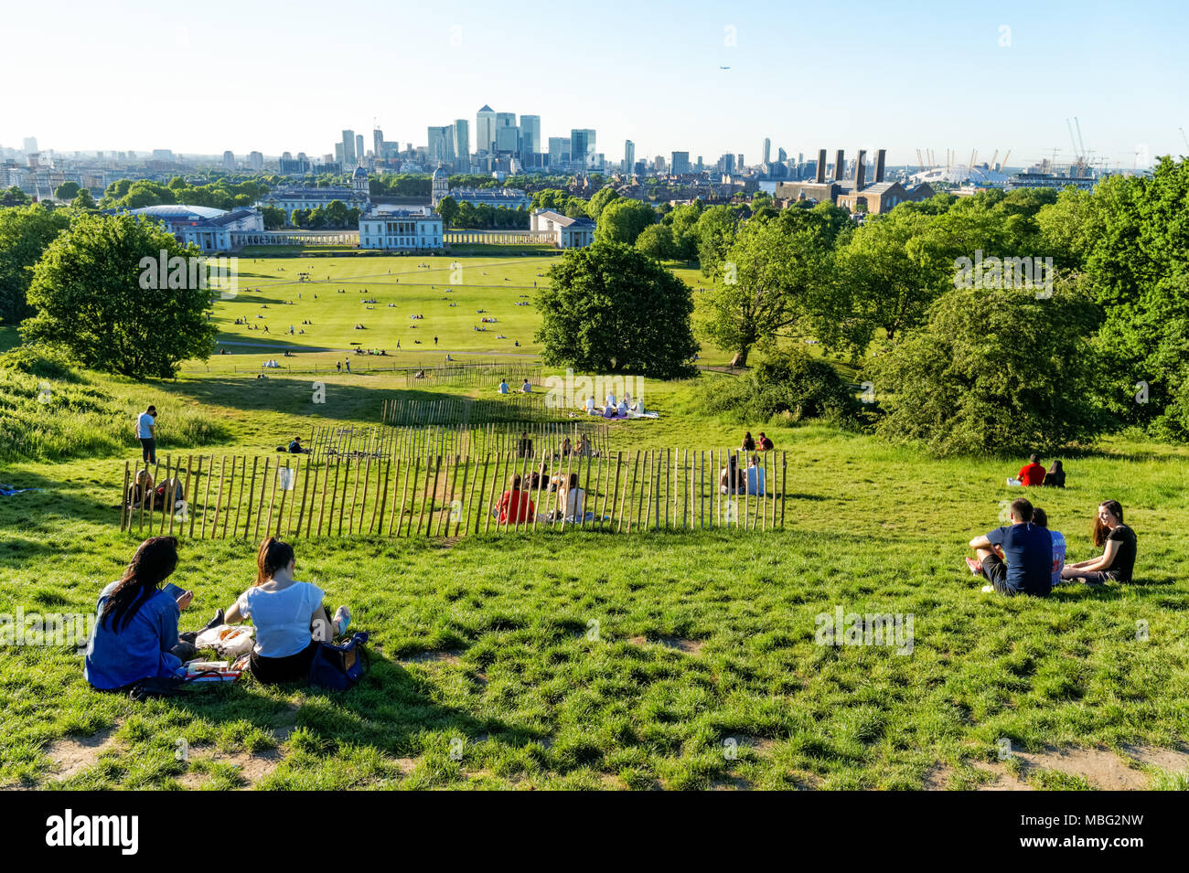 Menschen auf einem Hügel im Greenwich Park in London mit Canary Wharf im Hintergrund, England, Vereinigtes Königreich, Großbritannien Stockfoto