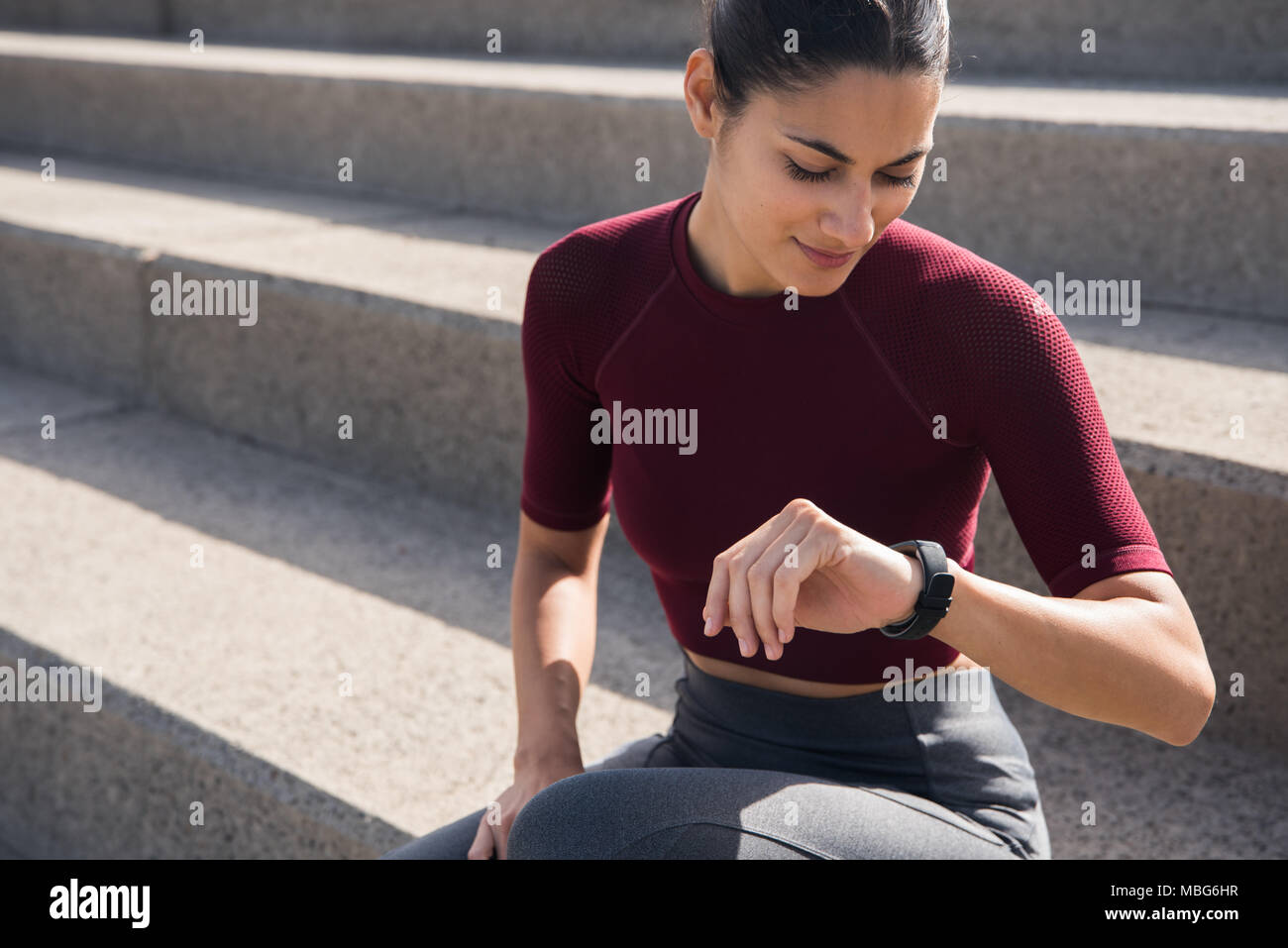 Junge brunette Mädchen schaut auf eine Wand sitzend auf Treppen in Fitness Kleidung Stockfoto