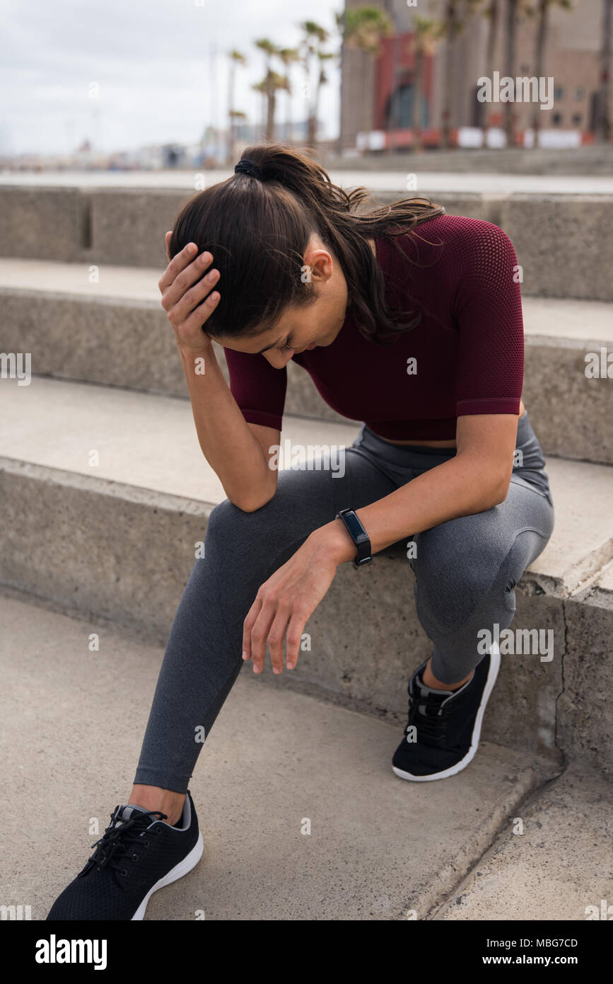 Junge sportliche Brünette sitzen auf der Treppe tragen graue Strumpfhose  kastanienbraunen, Hemd und schwarze Turnschuhe Stockfotografie - Alamy