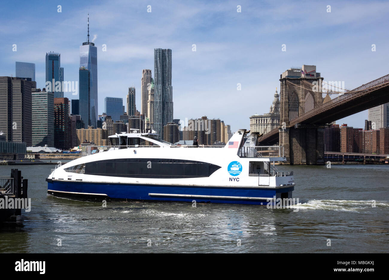 Ein NYC Fähre, die Dumbo Brooklyn Dock in den East River in New York mit der Skyline von Manhattan über den East River. Stockfoto