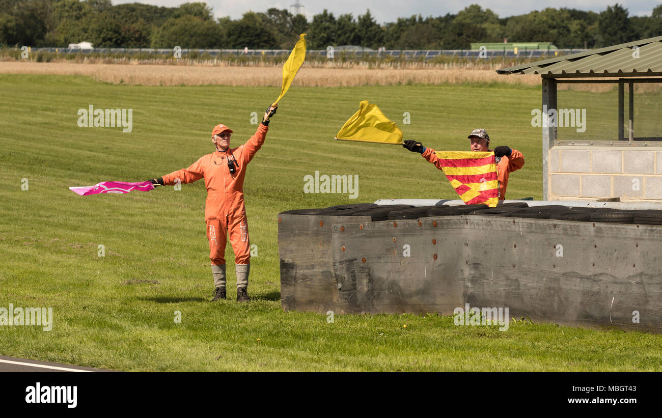 Flagge Marshals in Aktion auf Post 11 in Castle Combe Circuit, Wiltshire, Großbritannien Stockfoto