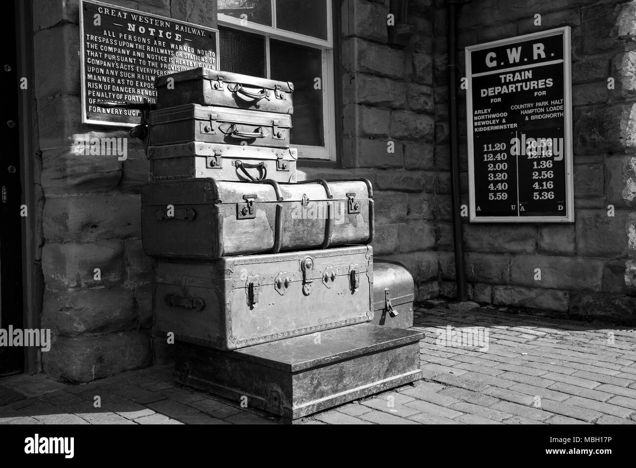 Monochromes 1940er-Jahre-Kriegsgepäck, Vintage-Gepäck. Gestapelte Koffer und altmodischer Kofferraum auf dem Bahnsteig des historischen Bahnhofs, Severn Valley Railway, Großbritannien. Stockfoto