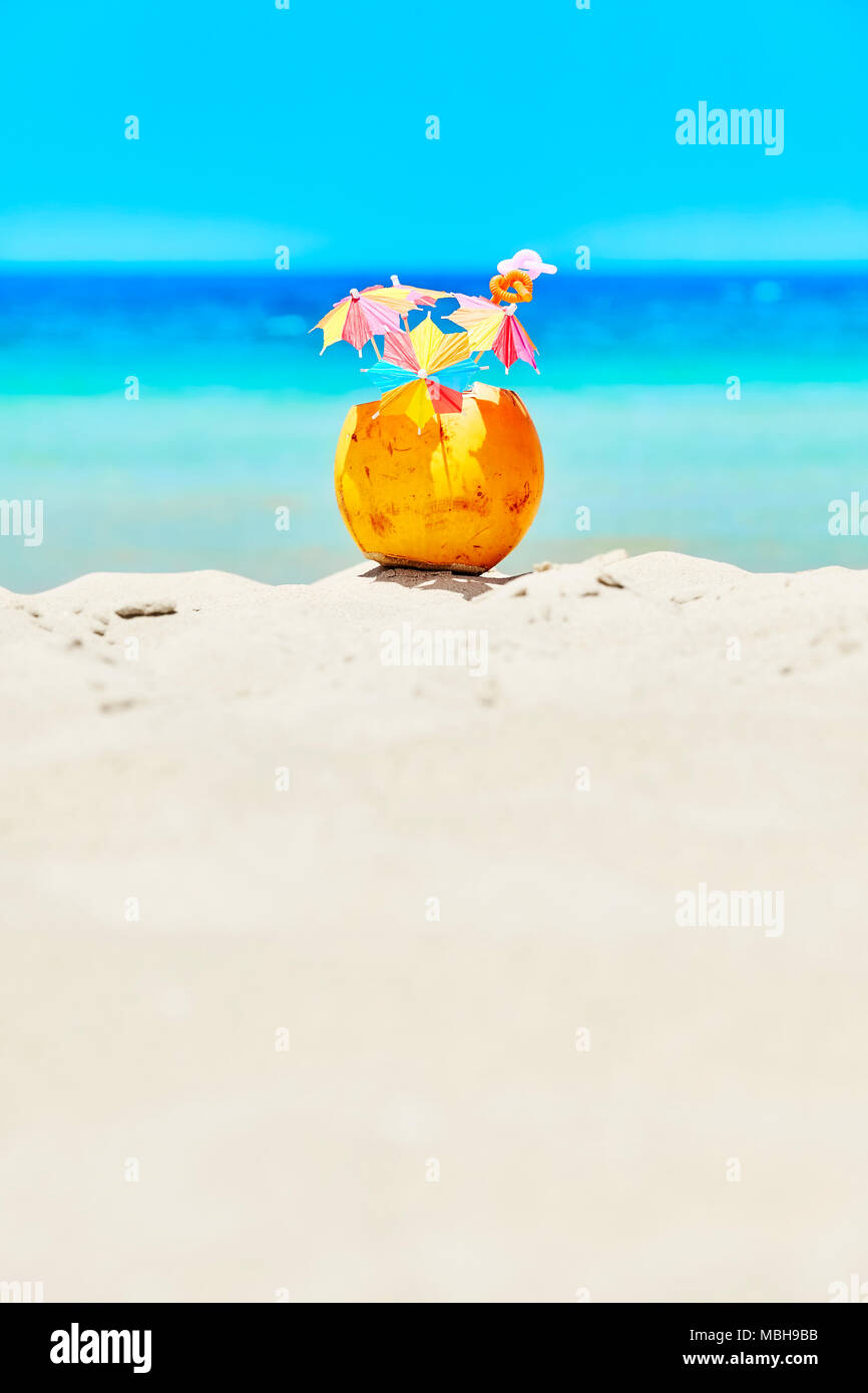 Kokosnuss mit bunten Sonnenschirmen und Strohhalme an einem Strand, Sommer Spaß Urlaub Konzept, selektiver Fokus, Platz für Text. Stockfoto