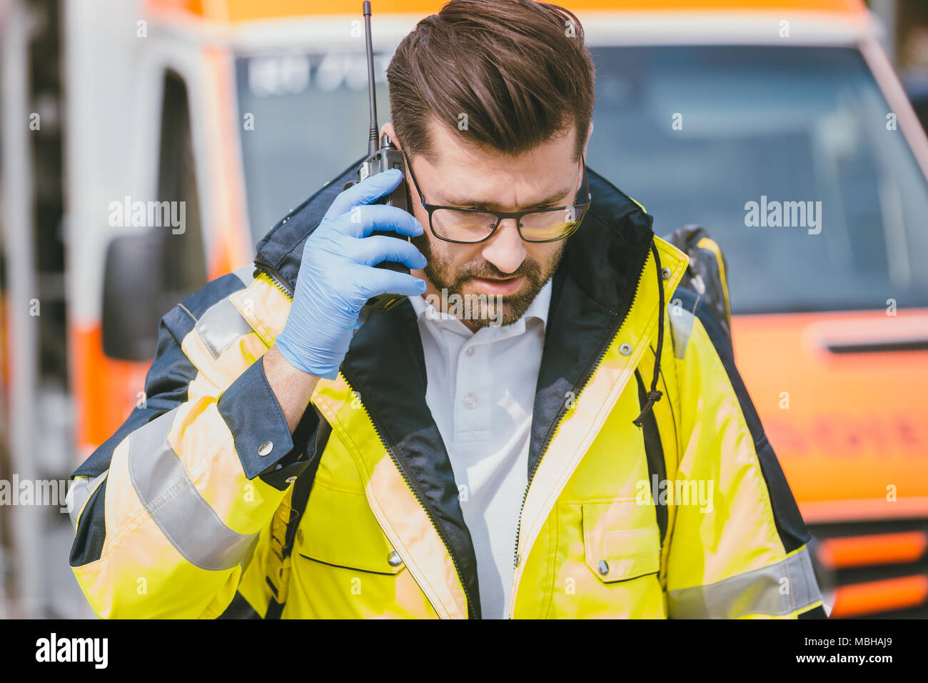 Medic im Gespräch mit der Zentrale über Radio vor der Ambulanz Stockfoto