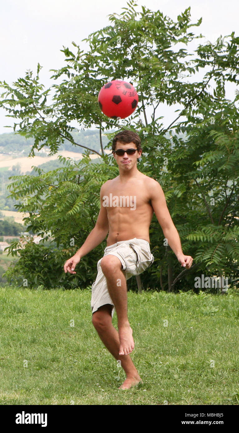 Barechested barfüssigen Jungen in Shorts dribbling Fußball in der Landschaft Stockfoto