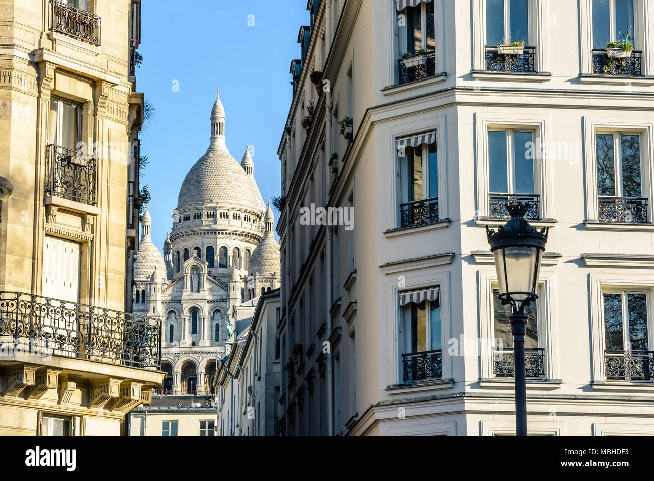 Die Basilika des Heiligen Herzen von Paris durch eine enge Straße zwischen typischen Gebäude mit einem Vintage Straße Licht im Vordergrund. Stockfoto