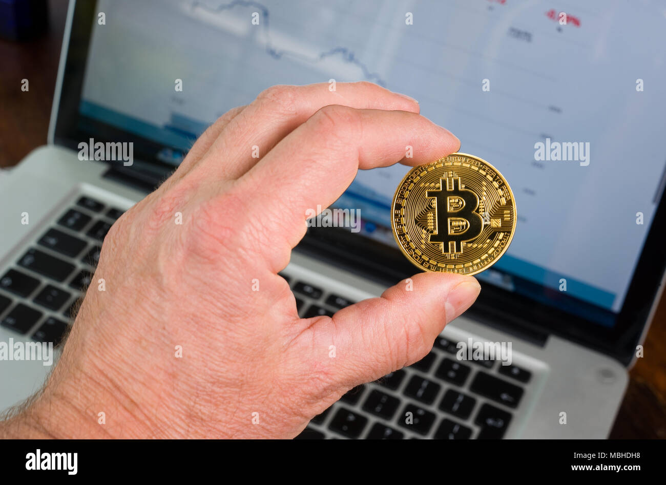 Bitcoin statt vor einem Laptop mit Preis trend graffic Stockfoto