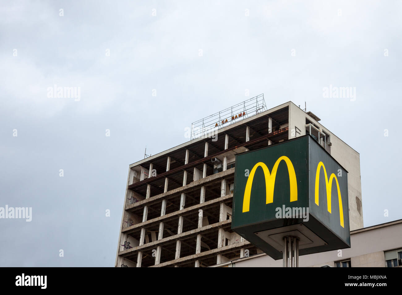 Belgrad, SERBIEN - 31. MÄRZ 2018: Mc Donald's Logo mit seinem Wahrzeichen M vor einem halben Gebäude in der Innenstadt von Belgrad Bild eines Mc Dona zerstört Stockfoto