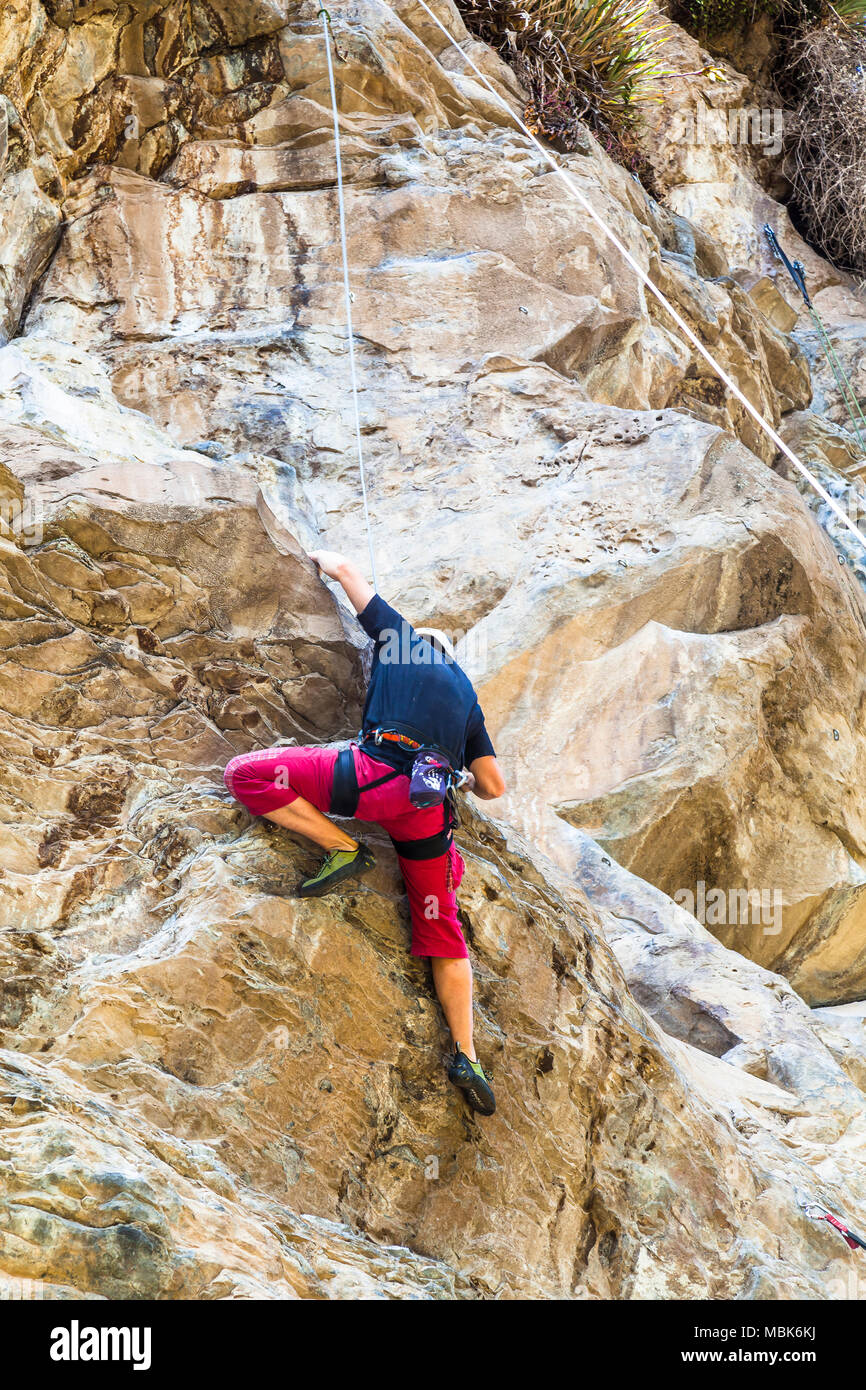 Junger Mann klettern auf eine Felswand Stockfoto
