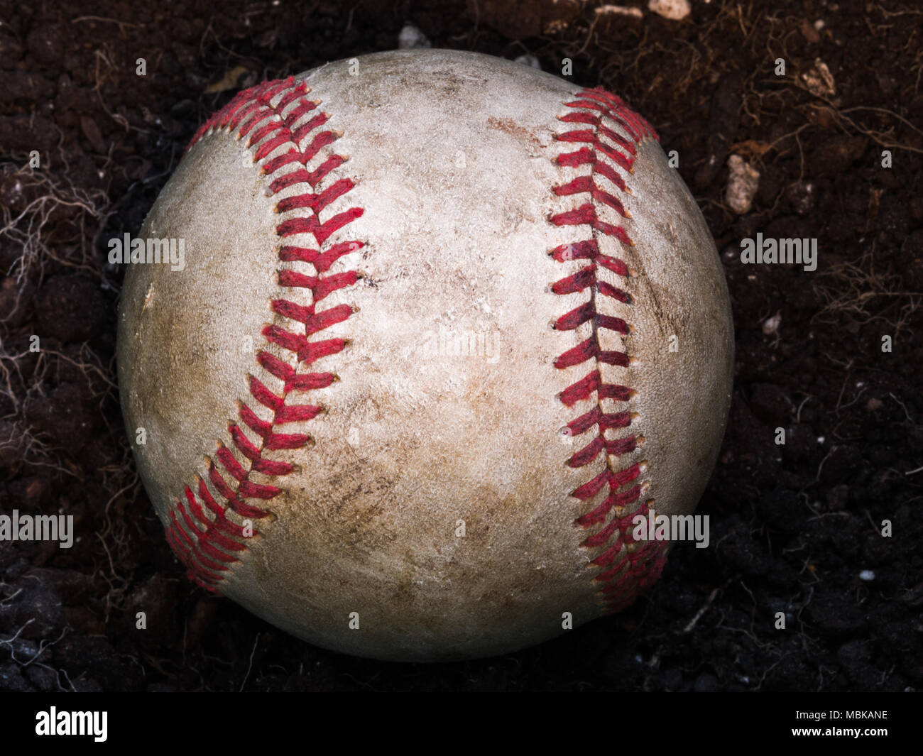 Close up Sport Hintergrund Bild eines alten verwitterten Leder baseball Verlegung in einem Haufen von braunen Schmutz mit komplizierten Details und roten Schnürsenkeln. Stockfoto