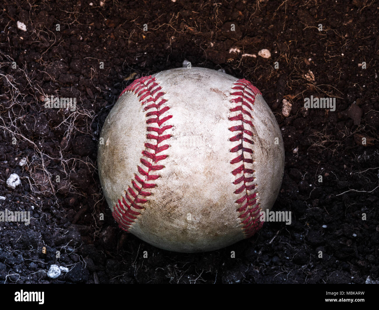 Close up Sport Hintergrund Bild eines alten verwitterten Leder baseball Verlegung in einem Haufen von braunen Schmutz mit komplizierten Details und roten Schnürsenkeln. Stockfoto