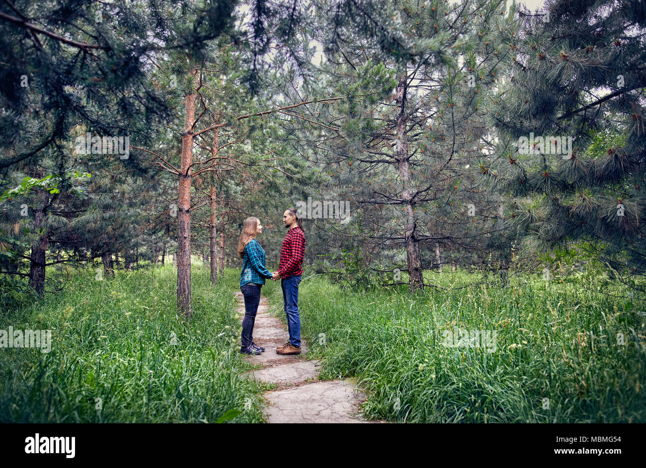 Junge hipster Paar in kariertem Hemd Jedes andere Holding von Hand in den Pinienwald. Liebe in der Natur. Stockfoto