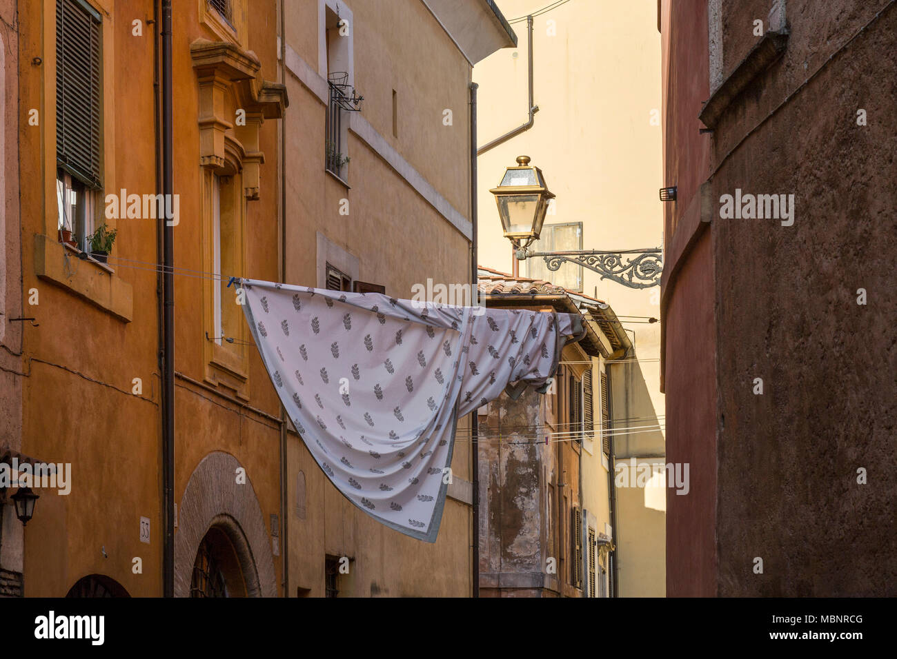 Ein Blatt auf eine Wäscheleine zwischen Gebäuden in Trastevere in Rom, Italien. Wäsche trocknen ist eine Ikone Blick über italienischen Straßen. Stockfoto
