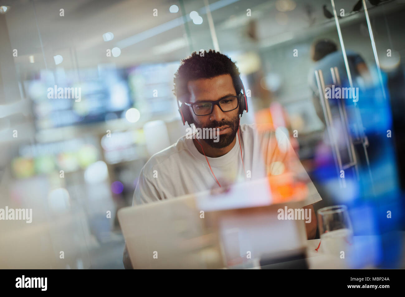 Kreative Geschäftsmann mit Kopfhörern am Laptop arbeiten im Büro ausgerichtet Stockfoto
