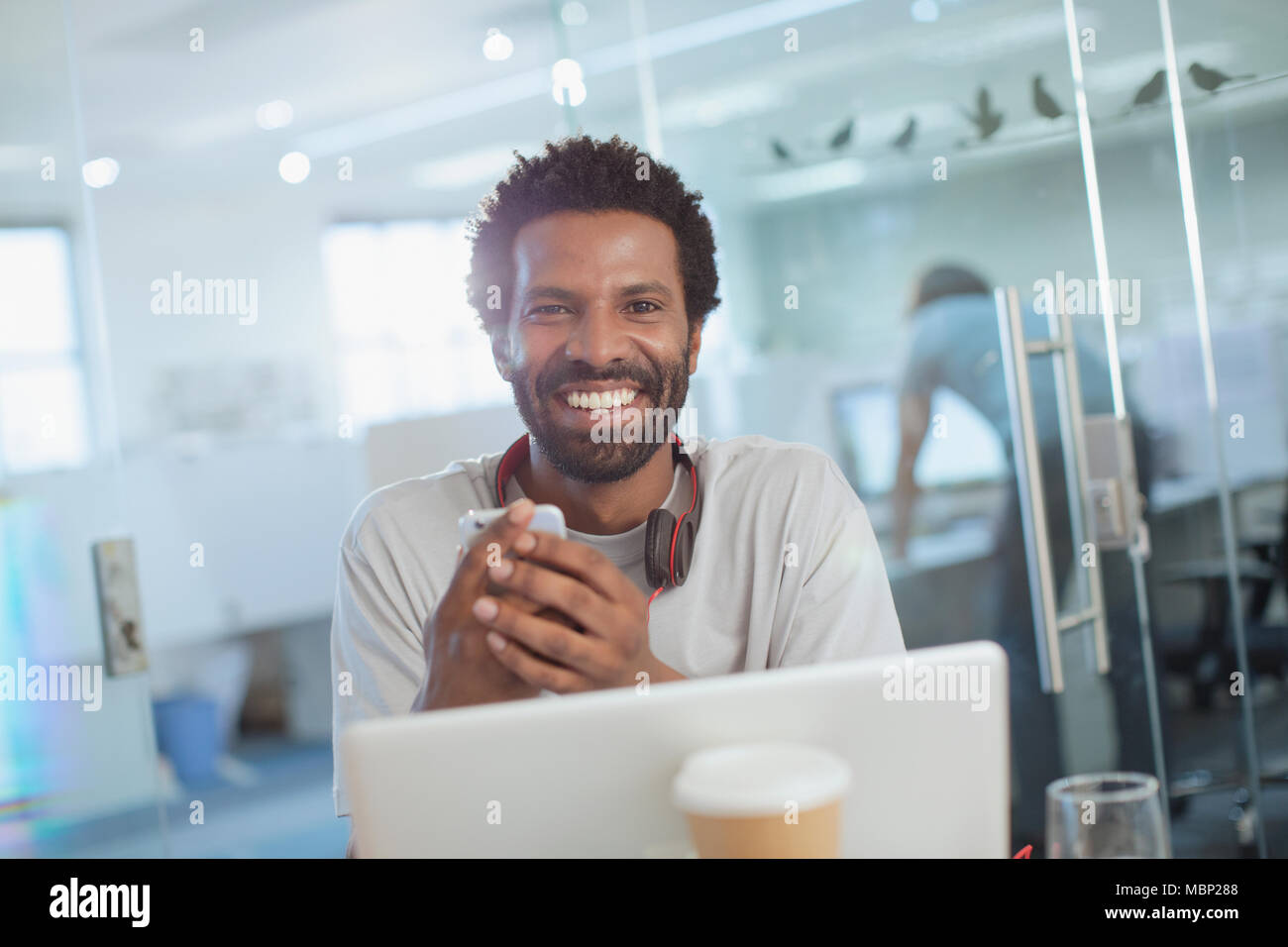 Porträt Lächeln, zuversichtlich, dass kreative Unternehmer mittels Smart Phone at Laptop im Büro Stockfoto