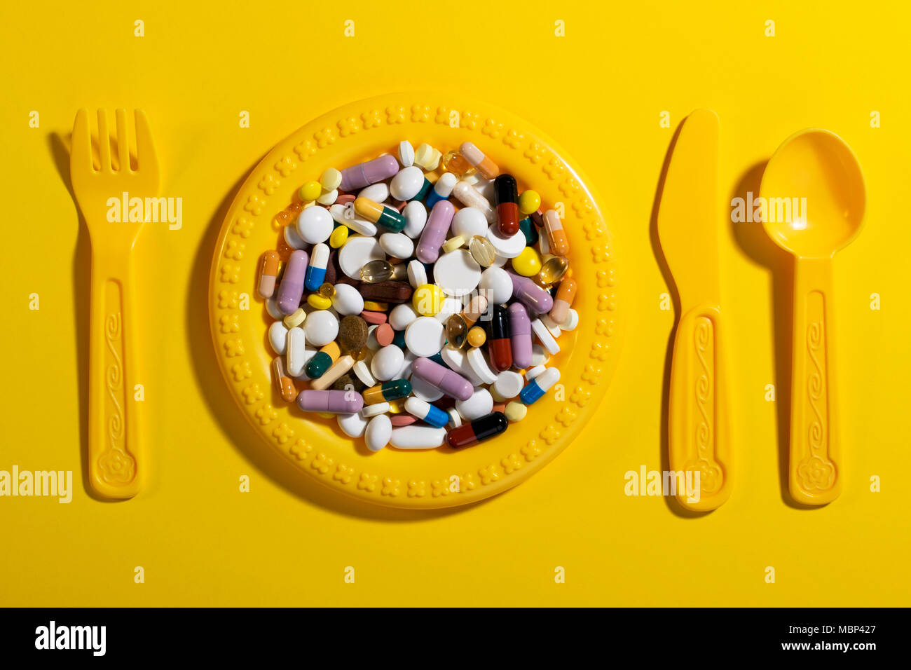 Kinder Teller mit Besteck mit bunten Pillen gefüllt. Konzept für eine Überdosis Medikamente in der Ernährung der Kinder. Stockfoto