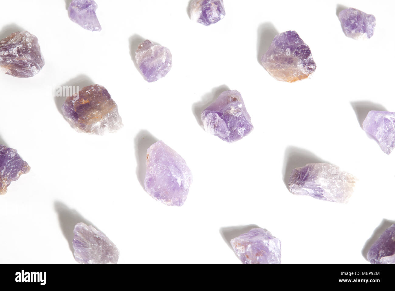 Einige Stücke roh Amethyst aufgereiht auf einem weißen Hintergrund. Minimale Farbe still life Fotografie. Stockfoto