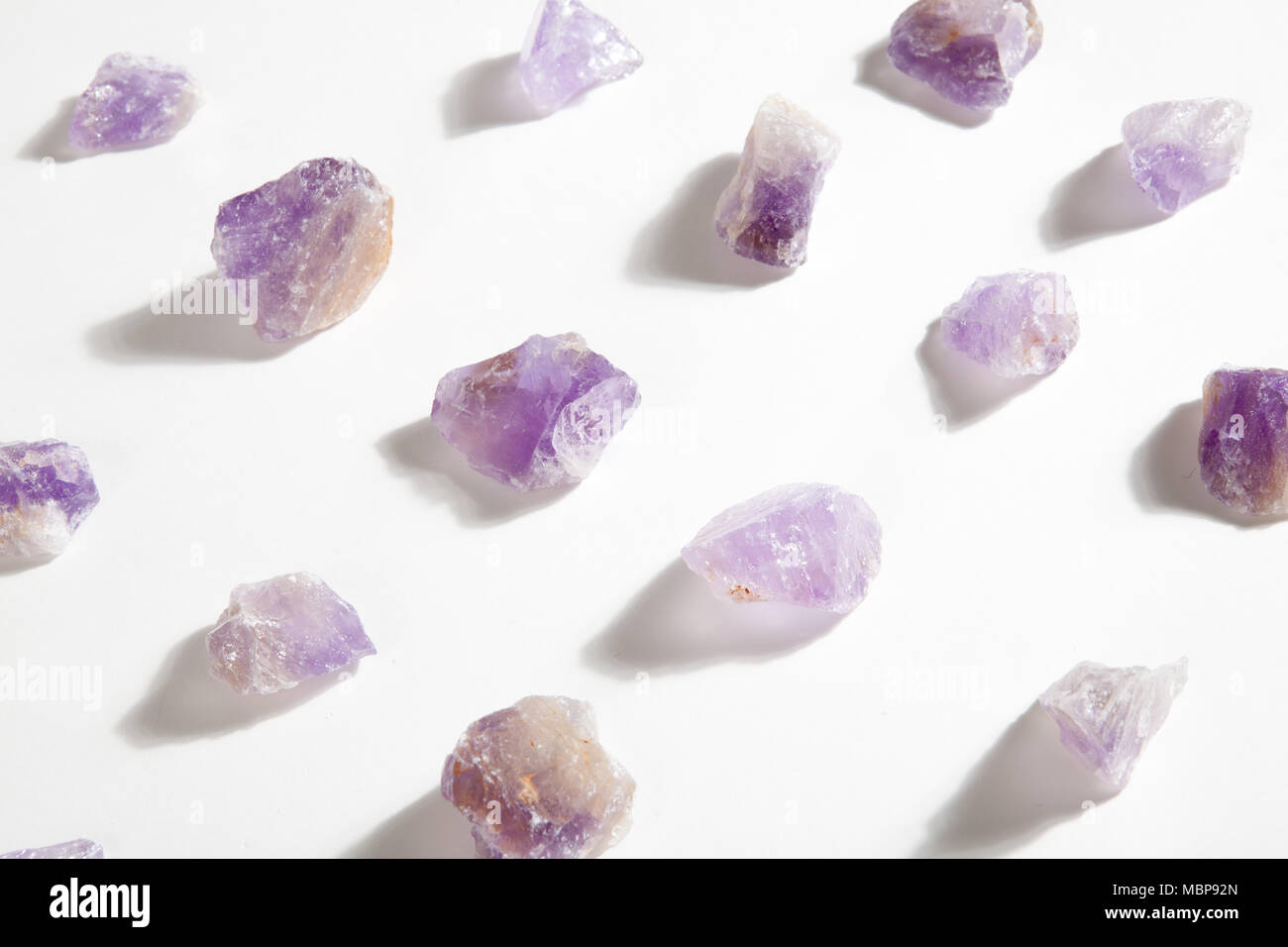 Einige Stücke roh Amethyst aufgereiht auf einem weißen Hintergrund. Minimale Farbe still life Fotografie. Stockfoto