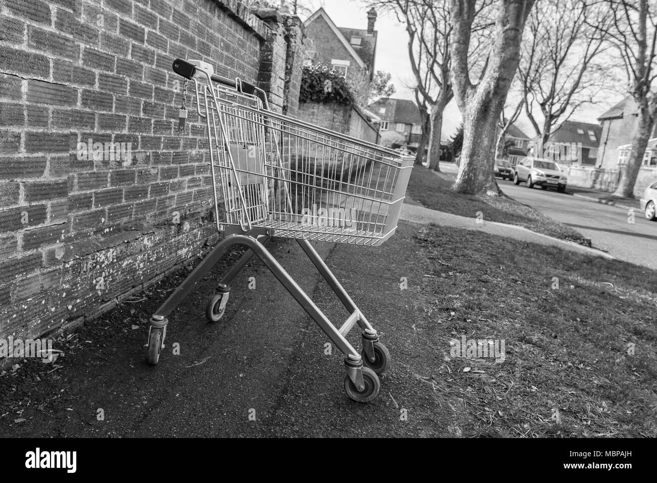 Supermarkt Einkaufswagen (Warenkorb) auf einer Straße in Großbritannien aufgegeben. Schwarz und Weiß, B&W, Monochrom. Stockfoto