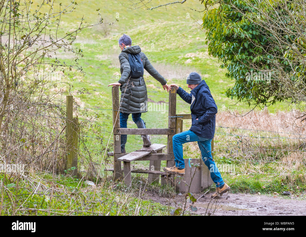 Paar klettern über eine hölzerne Stil auf dem Lande in West Sussex, England, UK. Stockfoto