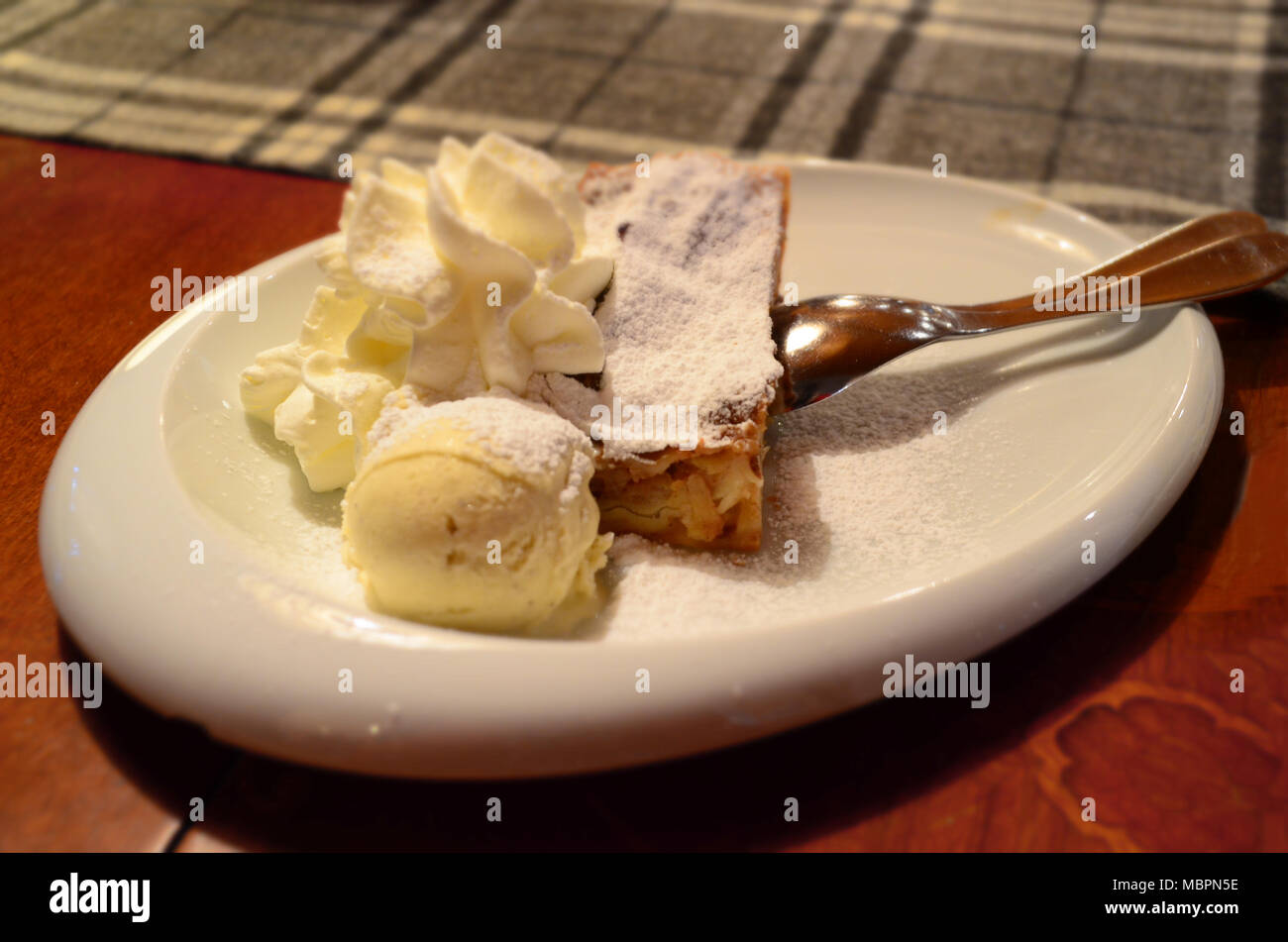 Traditionelle Apfelkuchen Apfelstrudel auf einer weißen Platte mit Eis und Sahne Stockfoto