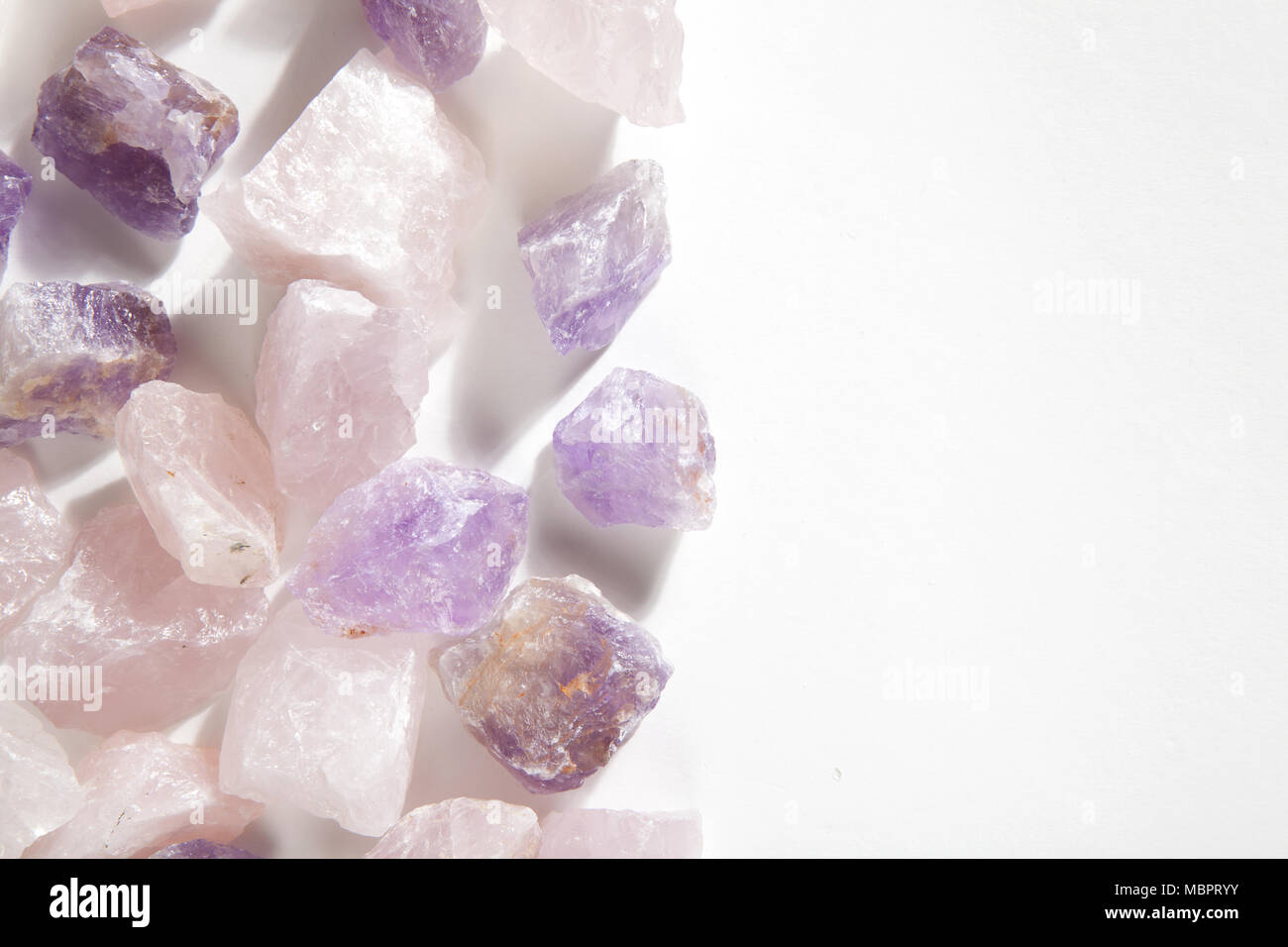 Einige Stücke roh Amethyst und rosenquarz wie ein Stapel auf einem weißen Hintergrund. Minimale Farbe still life Fotografie. Stockfoto