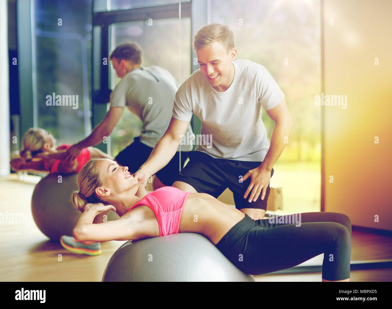 lächelnde junge Frau mit personal Trainer im Fitness-Studio Stockfoto