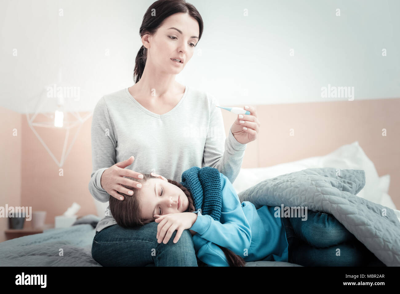 Sorgfältige lebendige Mutter sitzen und die Behandlung ihrer Tochter. Stockfoto