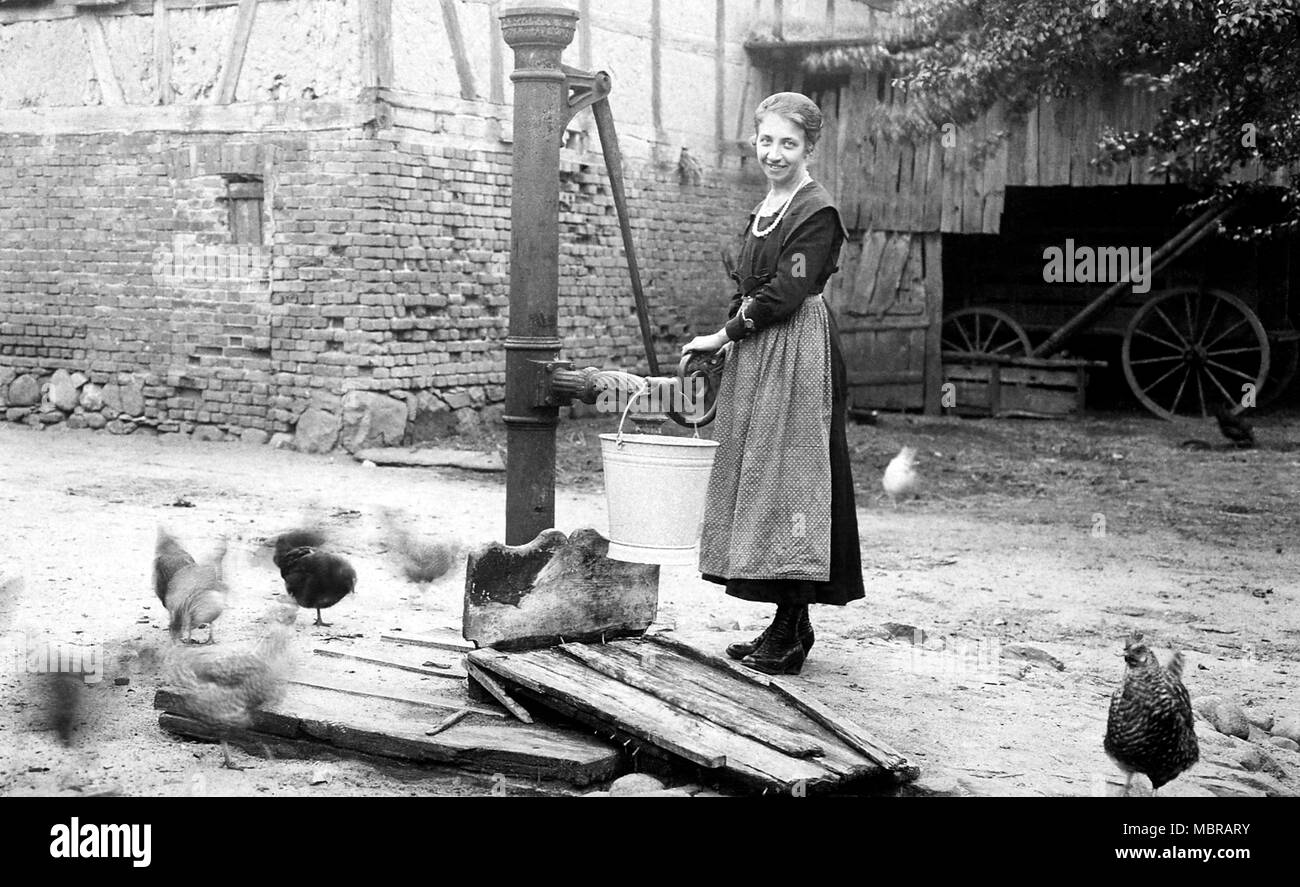 Bäuerin erhält Wasser aus einer Wasser-Pumpe, 1920er Jahre, Deutschland Stockfoto