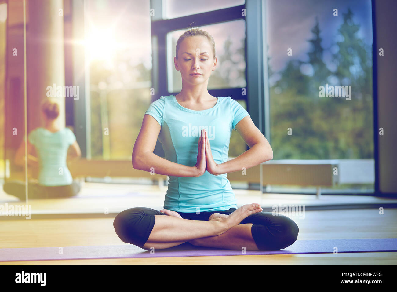 glückliche Frau meditieren im Lotus Pose auf Matte Stockfoto