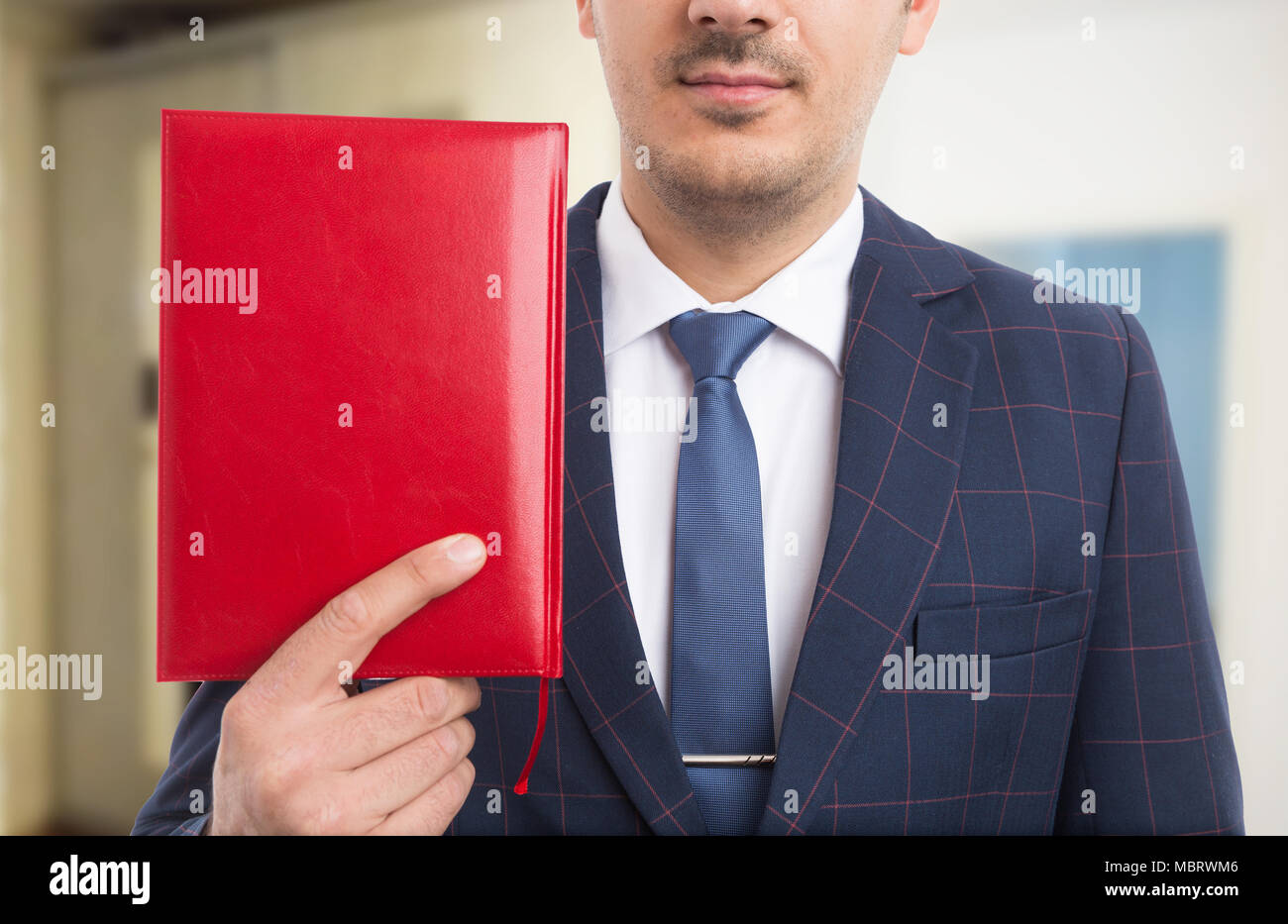 Anonyme Pastor halten roten Bibel oder Notebook als Gläubiger Konzept auf innen Hintergrund Stockfoto