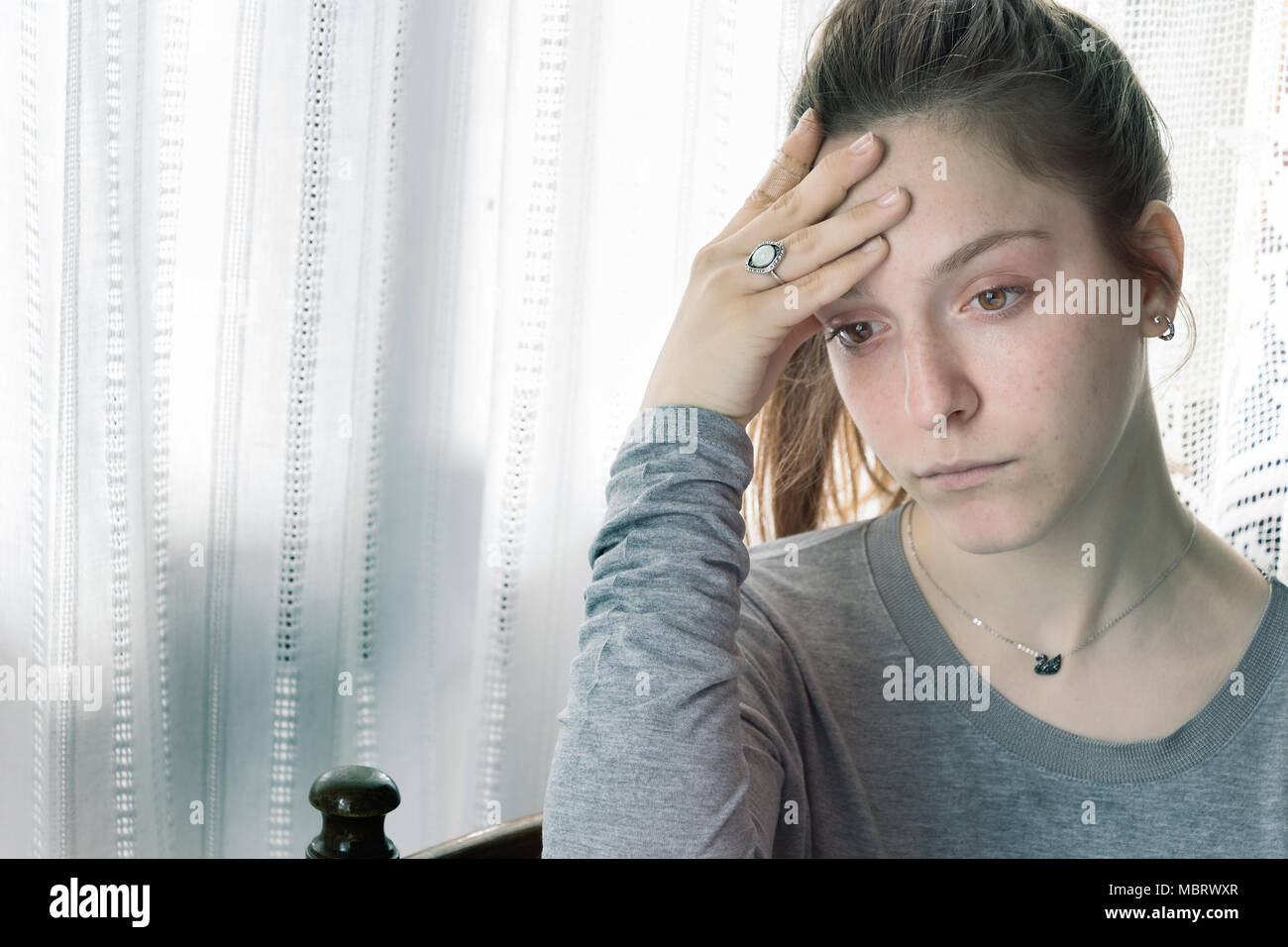 Jugendlicher Mädchen fast zu weinen, traurig zu Hause, mit der Hand auf die Stirn. Stockfoto
