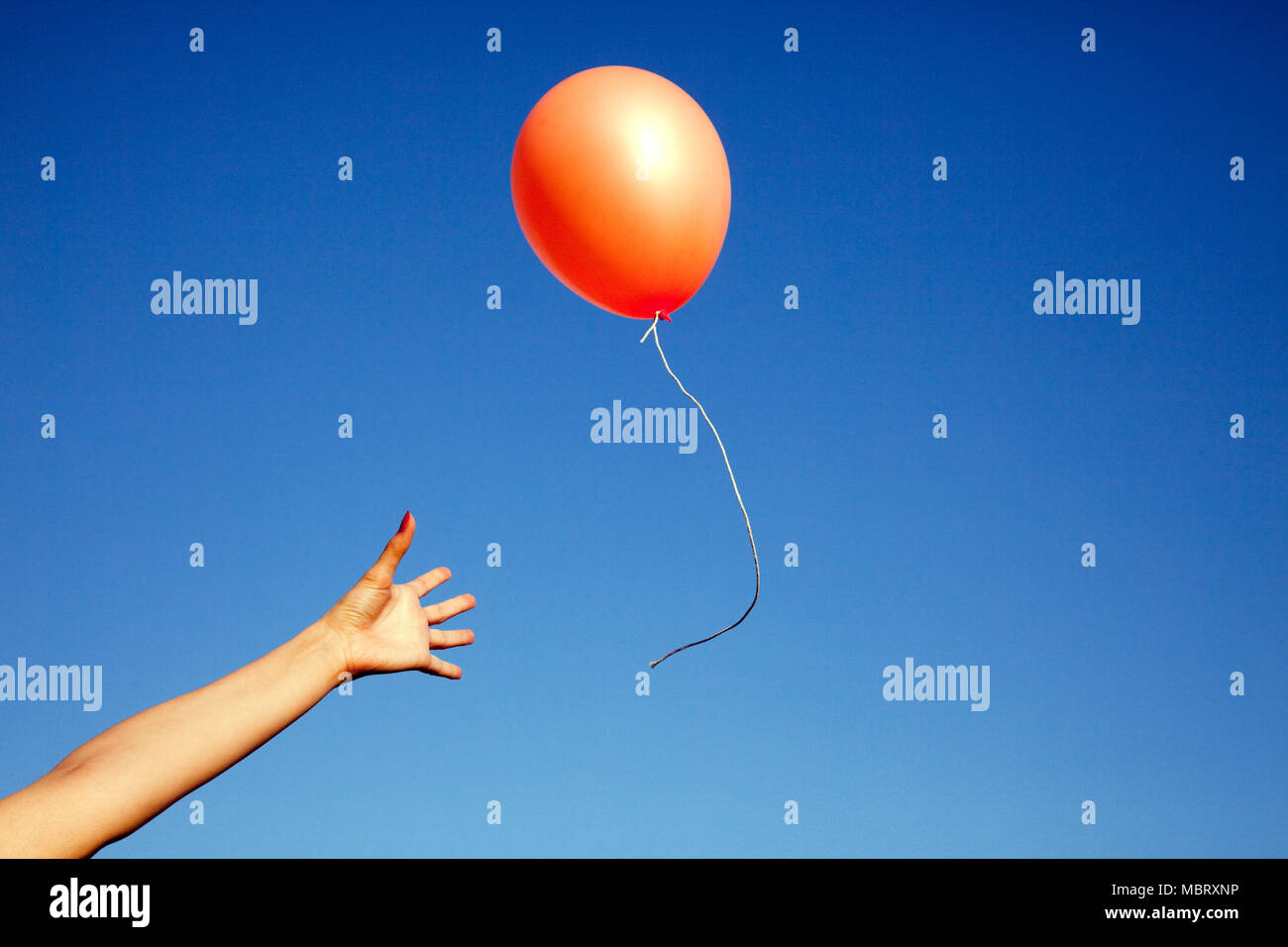 Hand Freigabe einer Orange Balloon Stockfoto