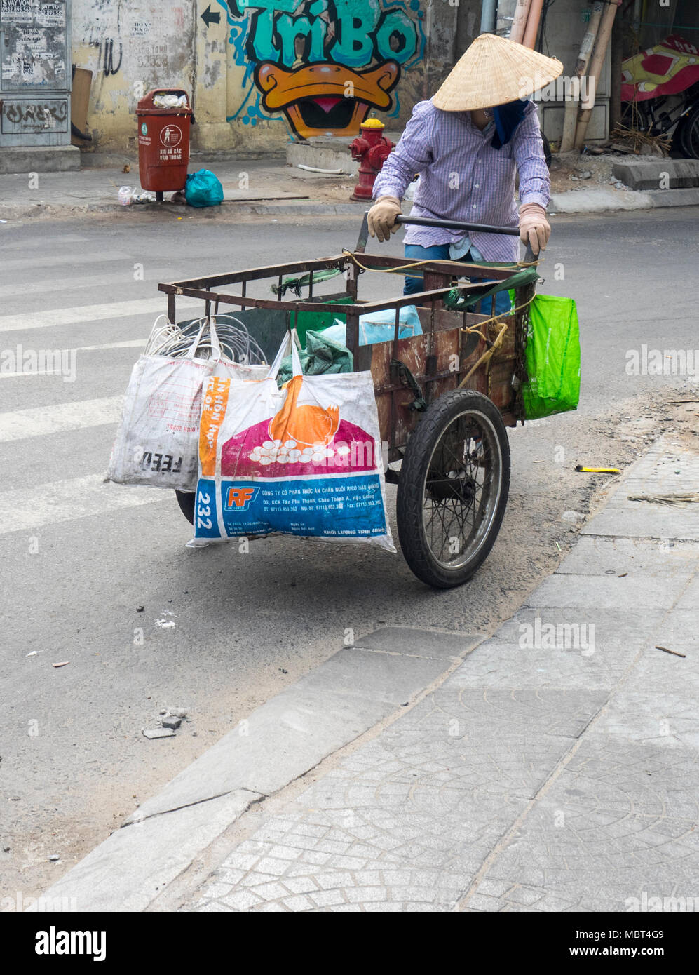 Eine vietnamesische Frau trug eine kegelförmige Hut, ein Dreirad Lastenrad in Ho Chi Minh City, Vietnam. Stockfoto