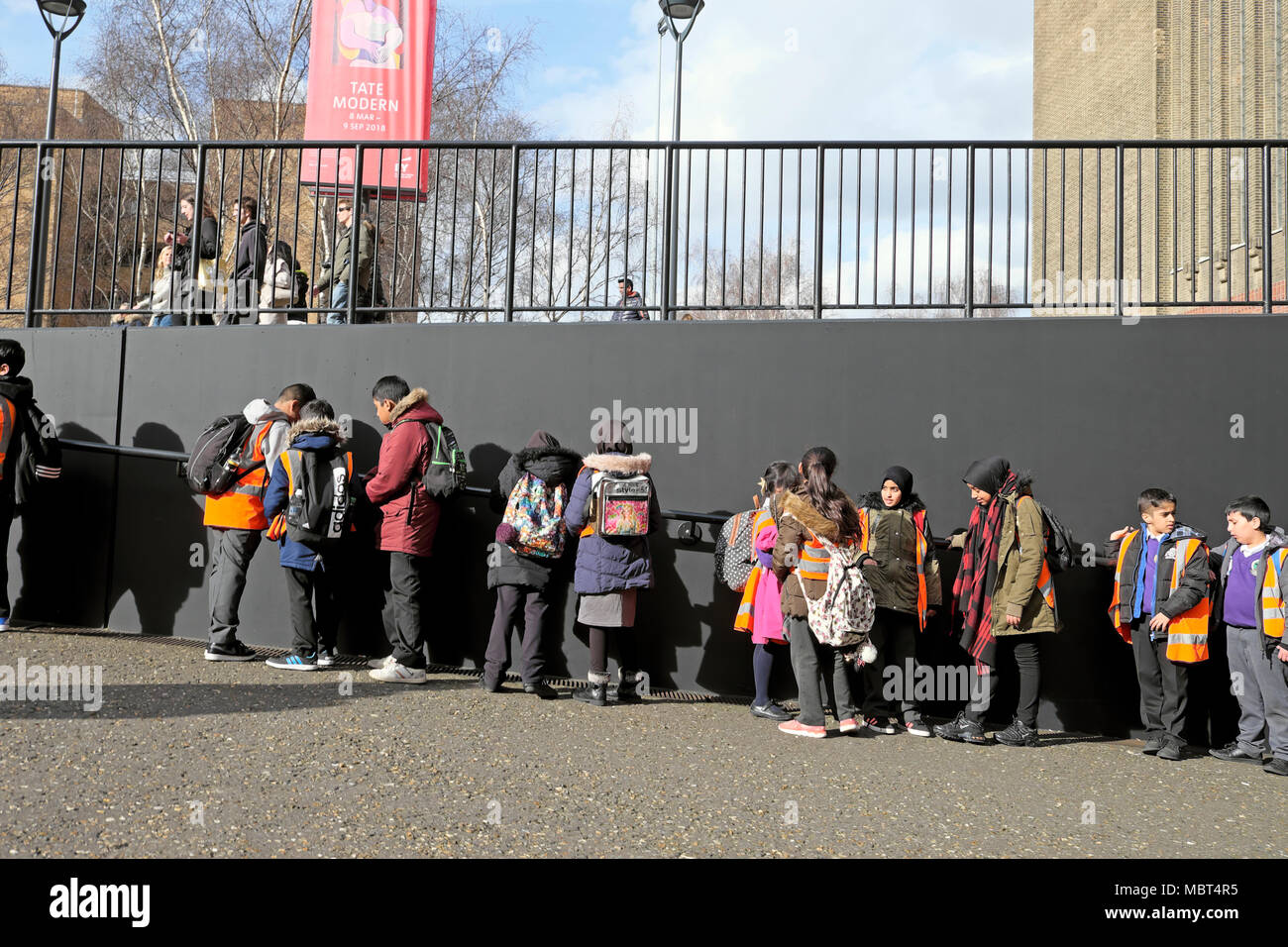 Eine Gruppe britischer Grundschulkinder besucht die Tate Modern Art Gallery Schlange am Bankside in South London, England Großbritannien KATHY DEWITT Stockfoto