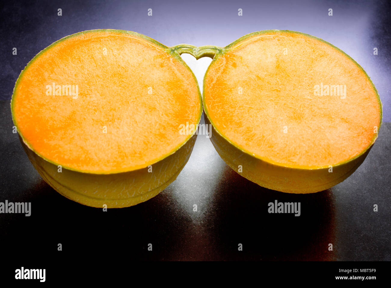 Der Raum zwischen zwei Hälften einer Melone und seinen Stiel bildet eine Herzform. Stockfoto