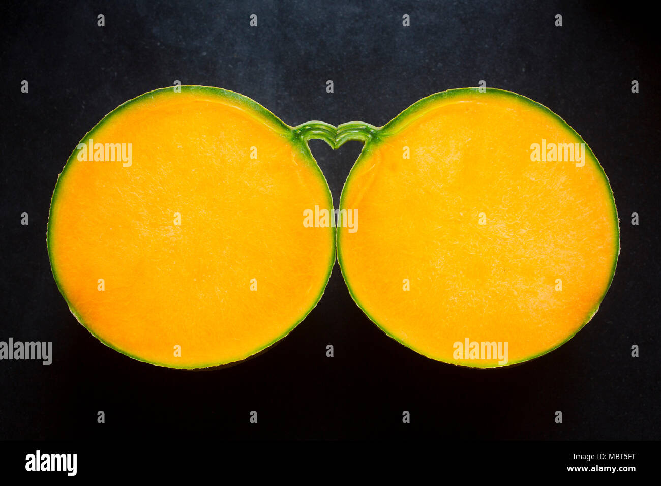 Der Raum zwischen zwei Hälften einer Melone und seinen Stiel bildet eine Herzform. Stockfoto
