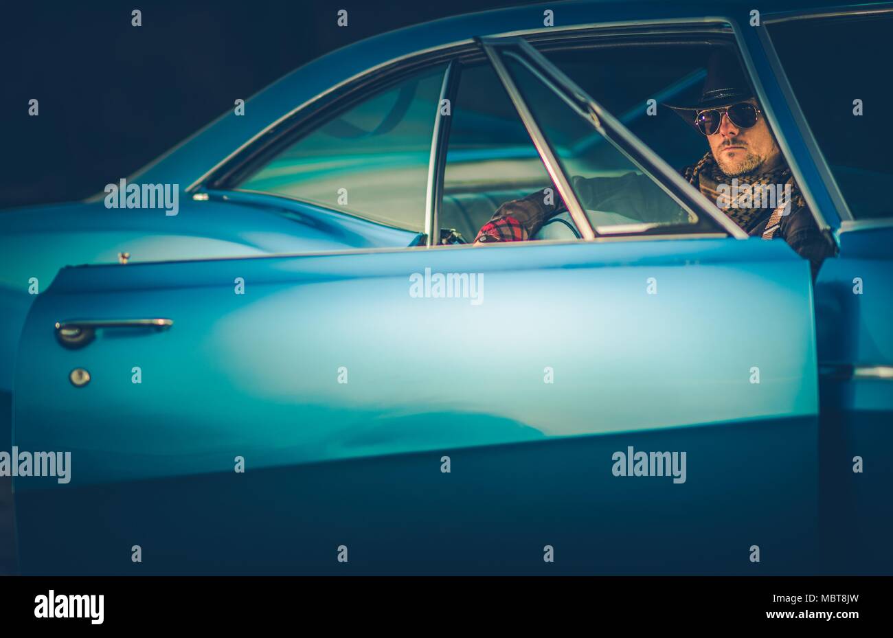 Texas Cowboy Classic fahren. Kaukasischen Männern in seinem 30s tragen westliche Kleidung enthalten Cowboyhut sitzen in seinem mächtigen Classic Muscle Car. Stockfoto