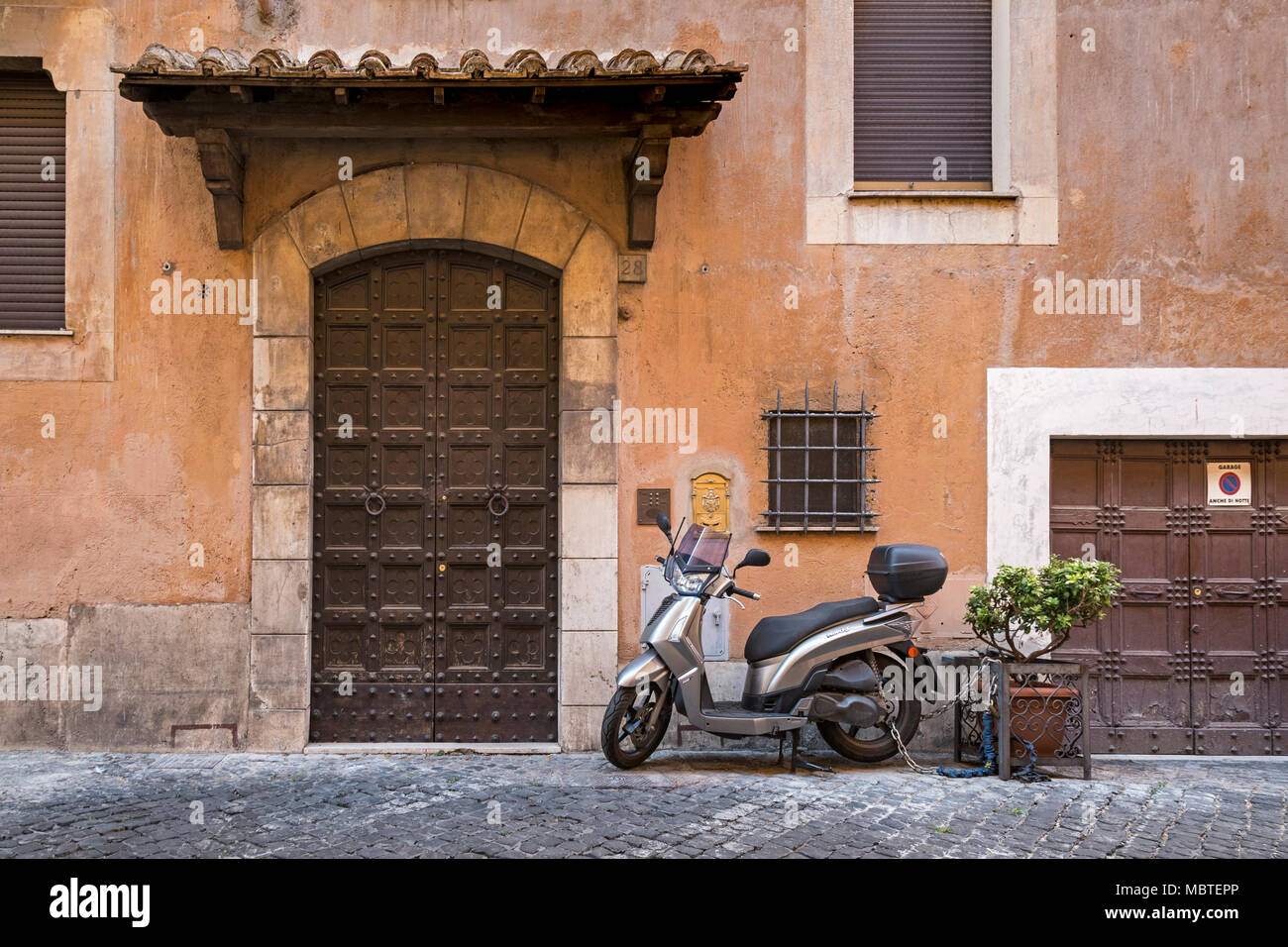 Ist die vordere Klappe groß oder das Garagentor klein? Eine Wohnstraße in Rom, Italien, die Fassade einer Villa mit verwitterten Fassade in den Farben Terra Stockfoto