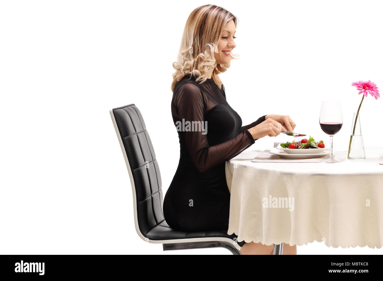 Junge Frau sitzt an einem Tisch im Restaurant und Essen auf weißem Hintergrund Stockfoto