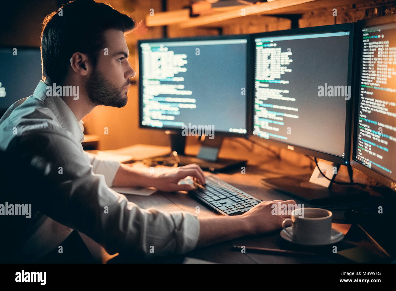 Schwerpunkt junge Entwickler coding spät im Büro schreiben Skript auf dem Computer Monitoren gezeigt, schwere stattlichen coder Programmer hacker Programmierung developi Stockfoto