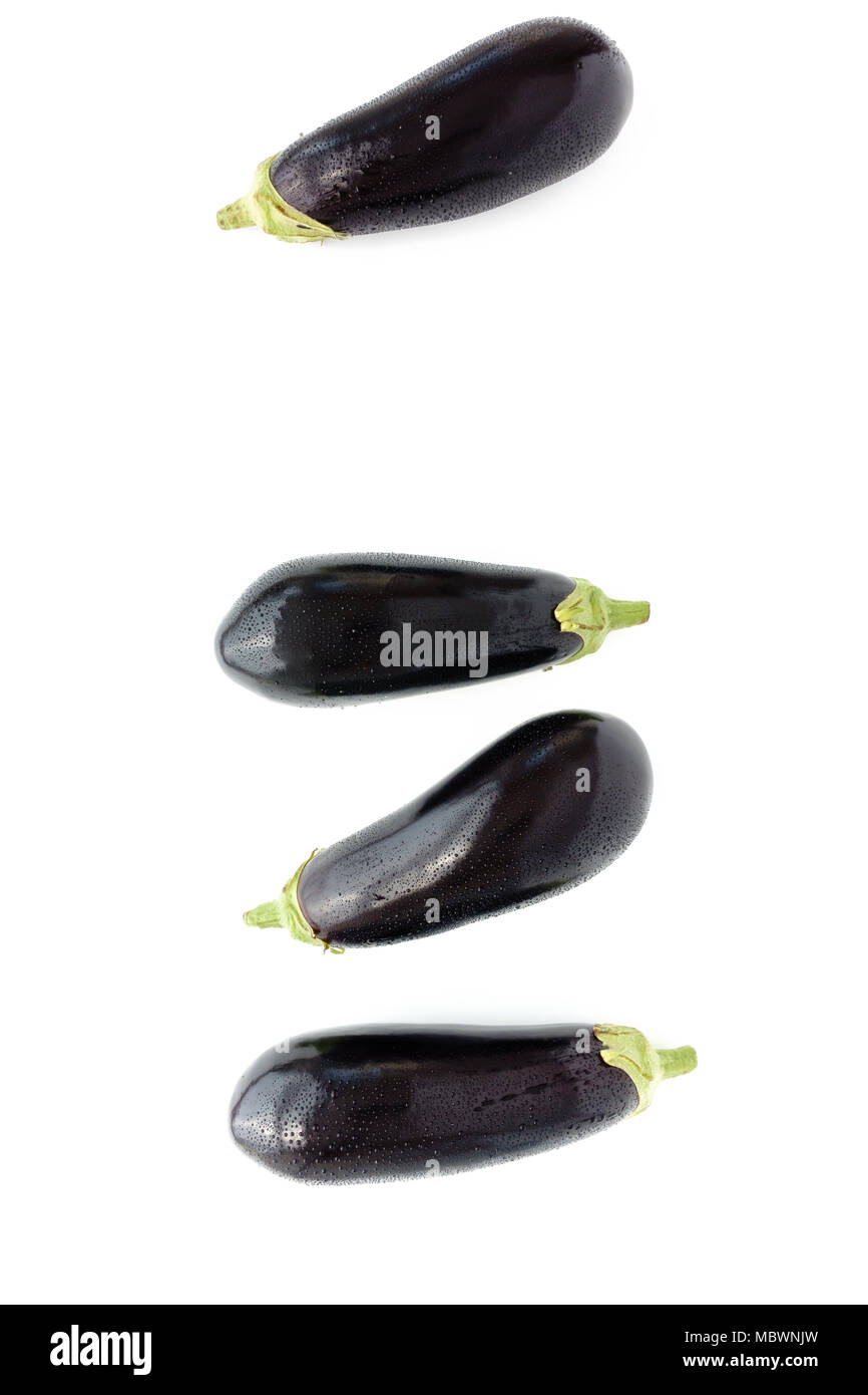 Nahaufnahme von vier ganze lila Auberginen mit Wassertropfen auf einem weißen Hintergrund. Ansicht von oben. Stockfoto