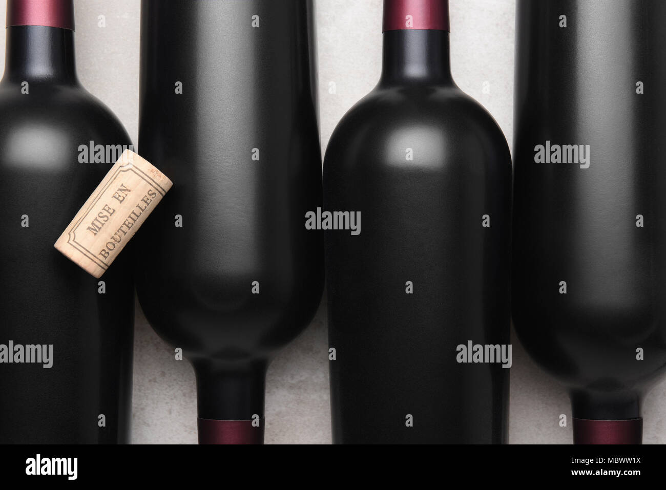 Nahaufnahme von vier roten Wein Flaschen und Korken mit den französischen Wörtern mis en Bouteilles, englische Übersetzung ist - bei der Flaschenabfüllung. Stockfoto