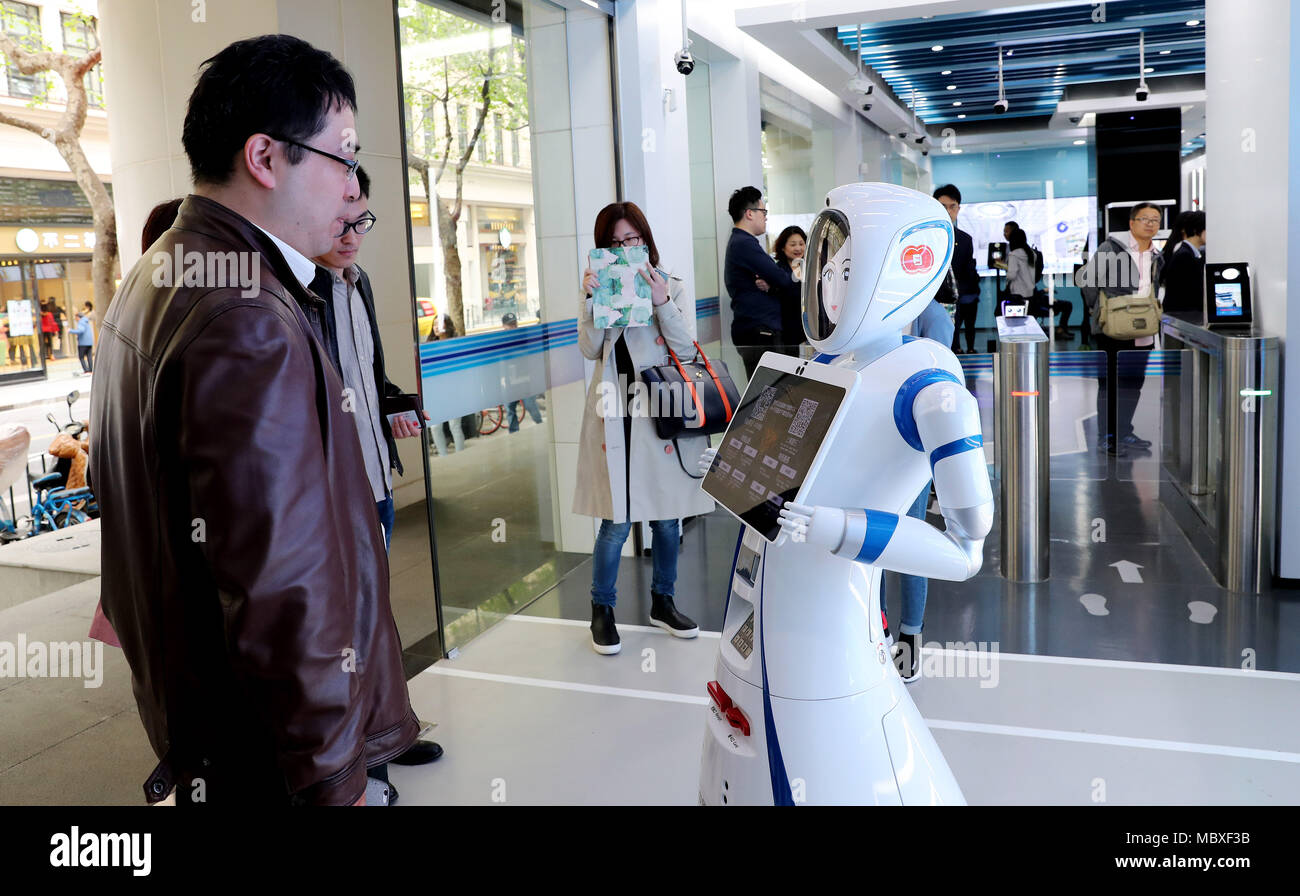 Shanghai, China. 12 Apr, 2018. Ein Kunde spricht mit einem Roboter am Eingang eines SB-Bereich der Jiujiang Road Zweig der China Construction Bank (CCB) in Shanghai, China, 12. April 2018. Kunden können 90 Prozent der Geld- und Transact-cash Business im SB-Bereich der Zweigstelle. Credit: Fang Zhe/Xinhua/Alamy leben Nachrichten Stockfoto