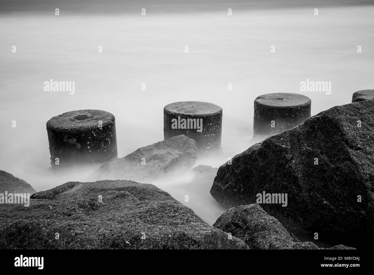 Pylone und Felsen Meer Wand mit konkreten defensive Blöcke und Wellen Stockfoto