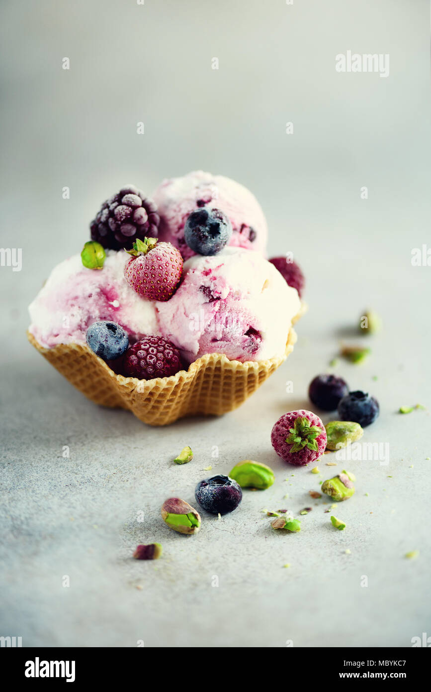 Rosa Eis mit Beeren, Erdbeeren, Blaubeeren, Himbeeren, Pistazien im Waffle basket. Sommer essen Konzept, kopieren. Gesund glutenfreie Obst Eis Stockfoto