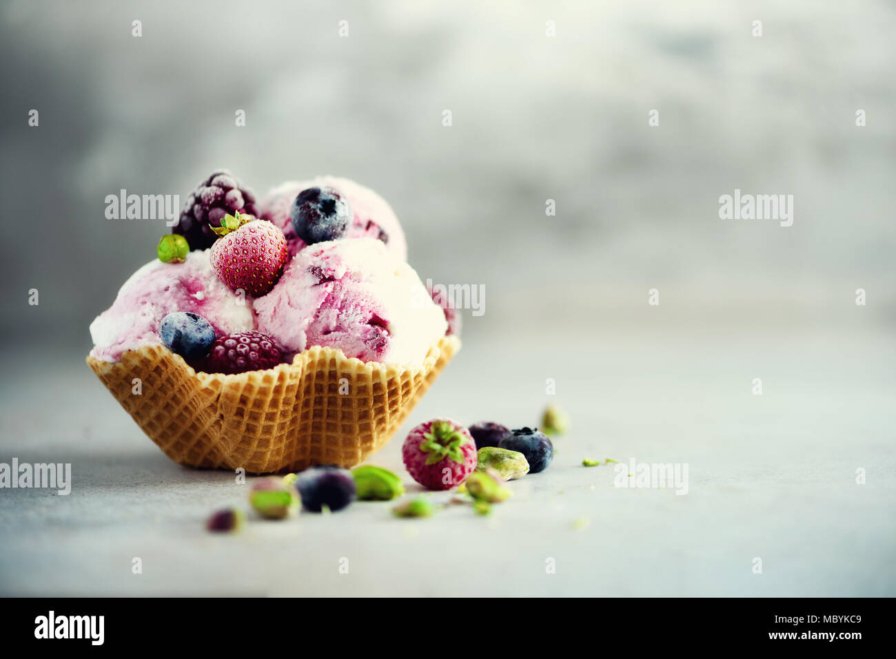 Rosa Eis mit Beeren, Erdbeeren, Blaubeeren, Himbeeren, Pistazien im Waffle basket. Sommer essen Konzept, kopieren. Gesund glutenfreie Obst Eis Stockfoto